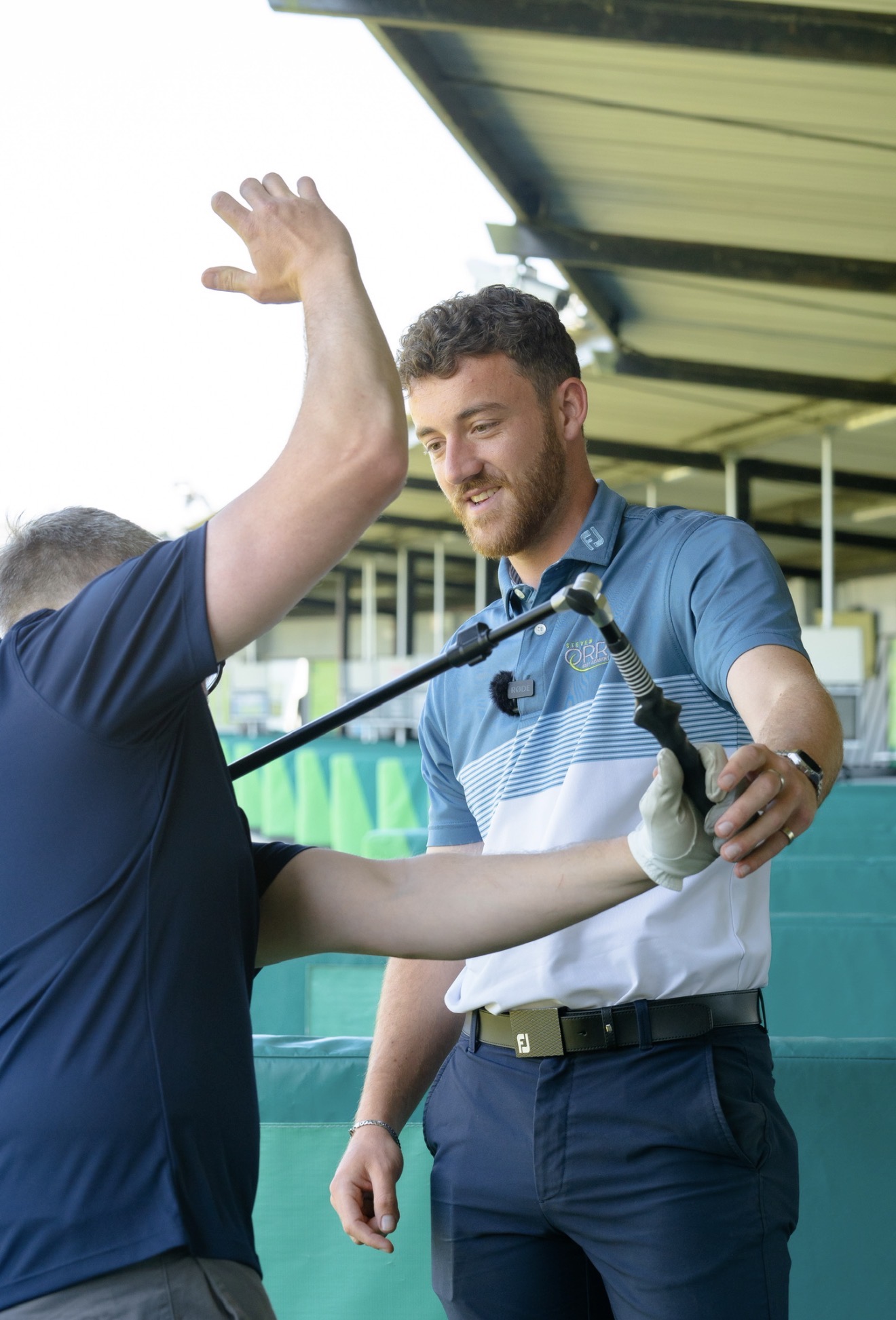 Jake Dunstan coaching a student on the driving range